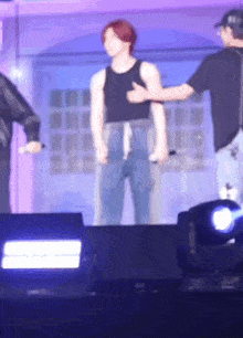 a man in a black tank top is standing on a stage with two other men