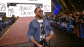 a wrestler named orange cassidy walks down a red carpet in front of a crowd
