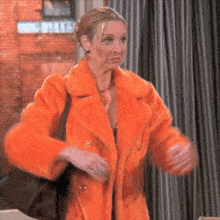 a woman is wearing an orange fur coat and carrying a black bag .