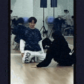 a man in a black tie dye shirt is kneeling down in a dance studio