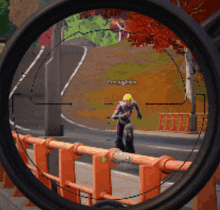 a sniper scope shows a person riding a motorcycle on a street