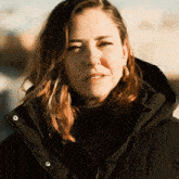 a close up of a woman wearing a black jacket with a hood