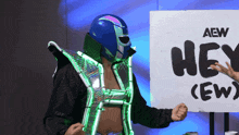 a wrestler stands in front of an aew sign