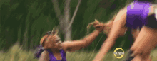 a woman in a purple tank top is holding another woman 's hand in a field .