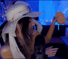 a woman wearing a white hat and ear buds is holding an orange object in front of a microphone