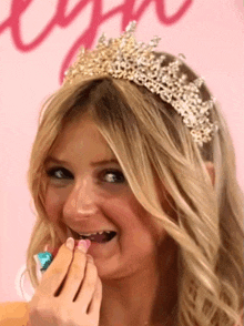 a woman with a tiara on her head is eating a candy