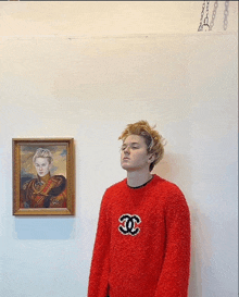 a man wearing a red sweater with a chanel logo