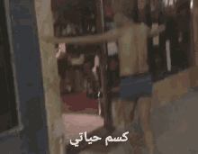 a shirtless man in blue underwear is standing in front of a door with arabic writing on it .