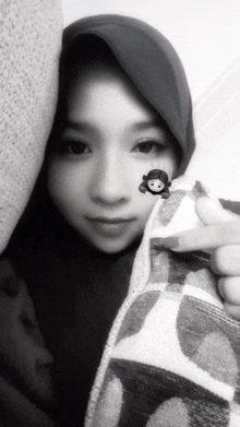 a black and white photo of a woman wearing a hijab and holding a blanket