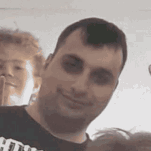 a man with a black eye is smiling for the camera while wearing a black shirt .