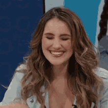 a woman with long hair is smiling while sitting in front of a microphone .