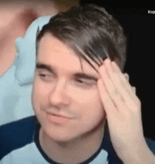 a man is holding his hand to his forehead .