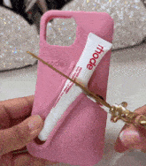 a pink phone case has a tube of hode lip treatment