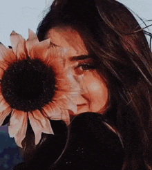 a woman is covering her face with a large sunflower .