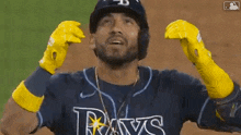 a baseball player for the rays is wearing yellow gloves and covering his face