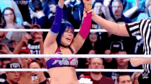 a female wrestler is giving a referee a high five in a wrestling ring .