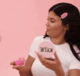 a woman in a white shirt is holding a pink circle with kylie written on it .