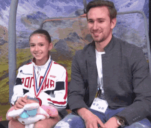 a man and a girl are posing for a picture with the girl wearing a medal that says russia