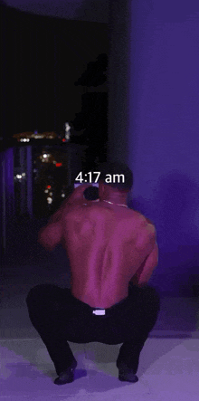 a shirtless man is standing in front of a purple background and holding a bottle of champagne