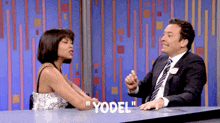 a man and a woman are sitting at a table with yodel written on it