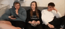 a group of young people are sitting on a couch watching a movie .