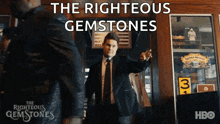 a man in a suit stands in front of a sign that says " the righteous gemstones "