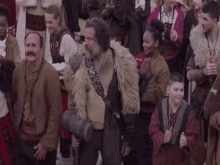 a man with a beard is holding a hammer in front of a crowd of people .
