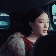 a woman in a fur coat is sitting in a car with her eyes closed