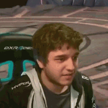 a young man is sitting in a gaming chair and making a face .