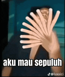 a man is covering his face with his hands with the words aku mau sepuluh written on the bottom