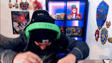 a man wearing green razer headphones and a black umi hat