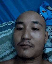a bald man with a beard is laying down on a bed