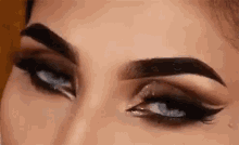 a close up of a woman 's eyes with smokey eye shadow and blue eyes .
