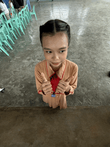 a little girl giving a thumbs up with a name tag on her chest