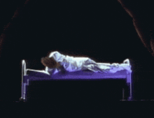 a person is laying on a bed with purple sheets