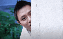 a young man peeking over a white wall