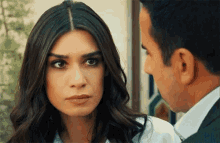 a man and a woman are looking at each other and the woman is looking at the man