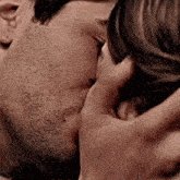 a man and a woman are kissing each other in a close up of their faces .