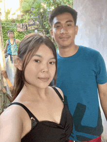 a man in a blue shirt with the letter l on it is standing next to a woman