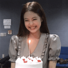 a woman is smiling while holding a birthday cake with a candle lit up