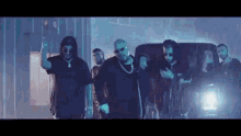 a group of men are standing next to each other in front of a van in a dark room .