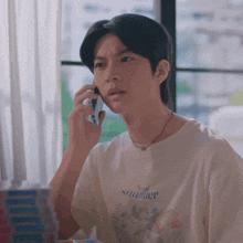 a young man wearing a floral summer t-shirt talks on a cell phone