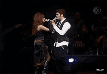 a man and a woman singing on a stage with rbd written on the back of the stage