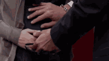 a man is touching a pregnant woman 's belly with his hand .
