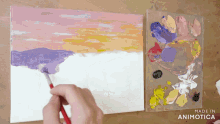 a painting of a sunset is being painted on a canvas by a person with a brush