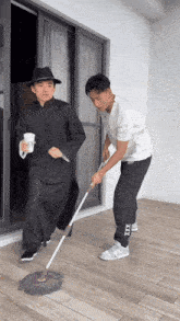 two men are cleaning the floor with a mop that says xxx on the side