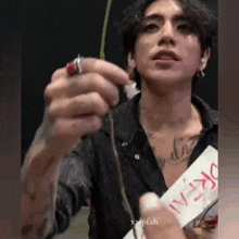 a man with a lot of tattoos on his body is holding a stick in his hand .