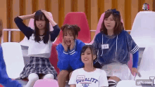 a group of young girls are sitting in a stadium with their hands on their faces .