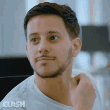 a man with a beard is wearing a white shirt with the word clash on the bottom