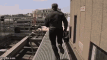 a man in a black jacket is running down a metal walkway with imgflip.com written on the bottom